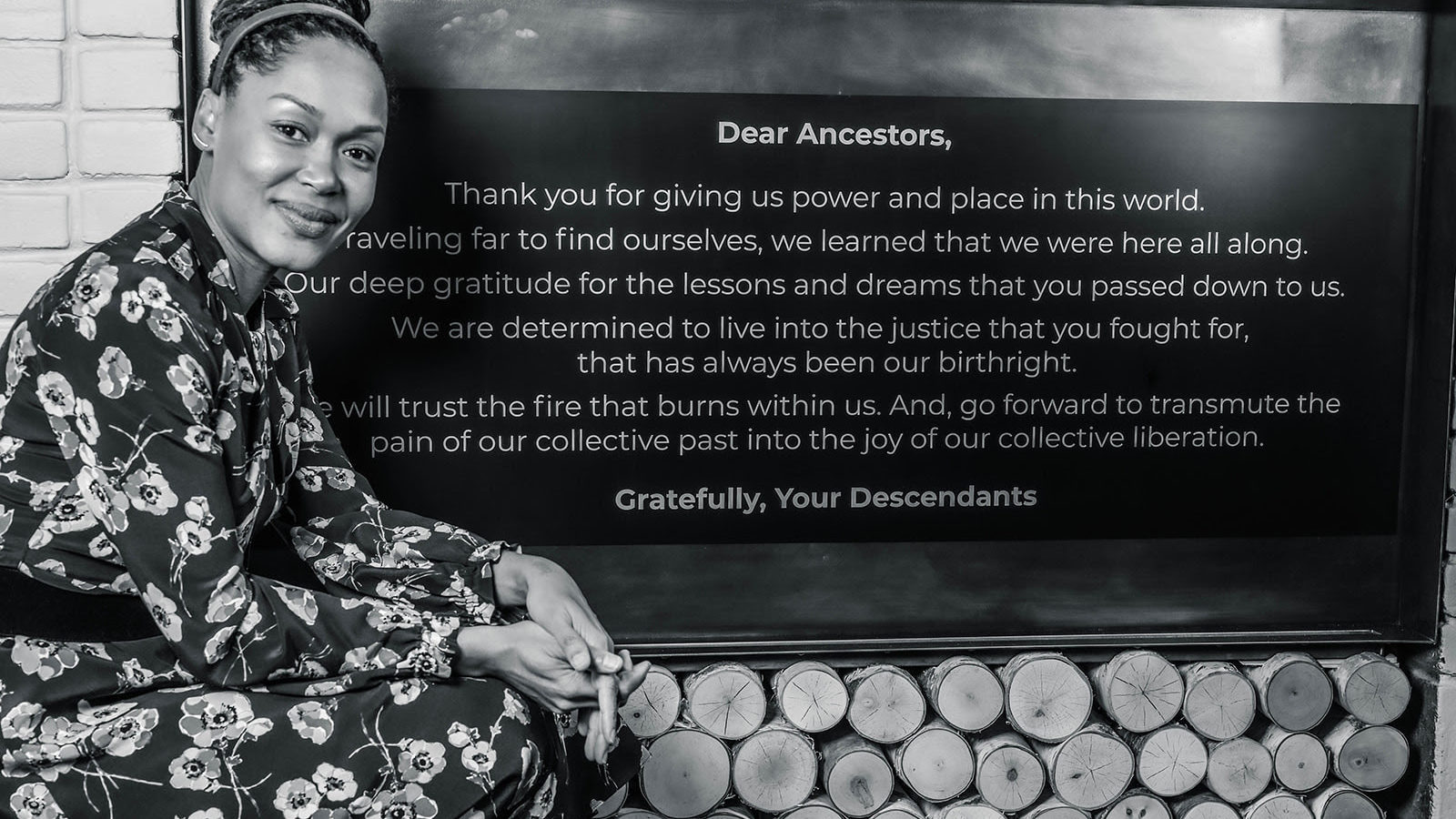 Andrea - farwell message Andrea looking into the camera sitting next to a plaque with a thank you to ancestors