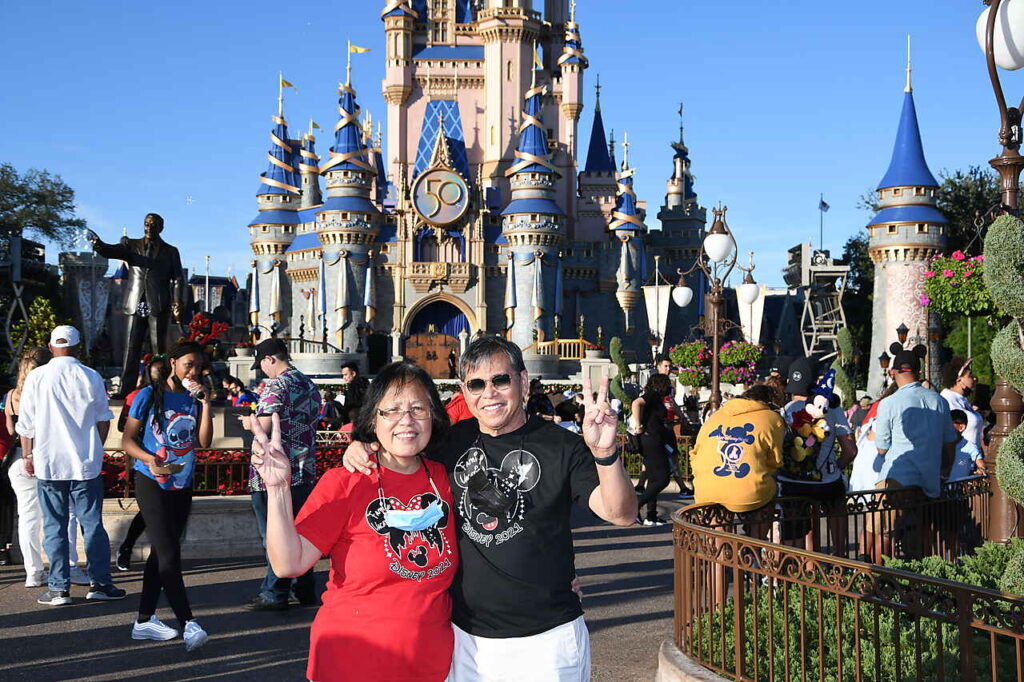 Lydia Jocson and her husband standing in front of the Disneyland castle.