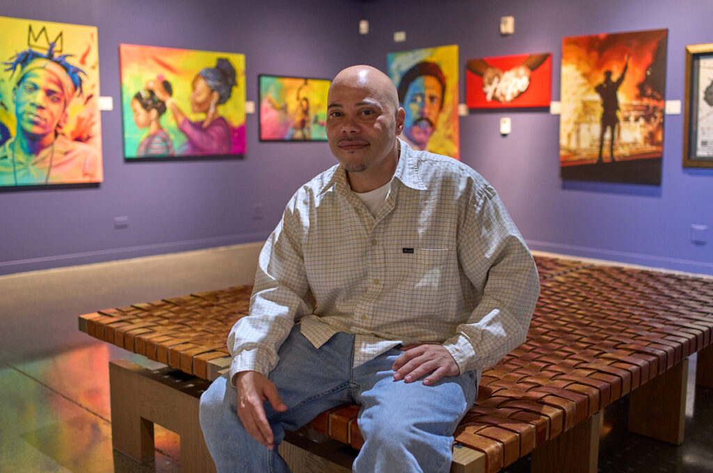 Man sitting on a table in front of a wall of art