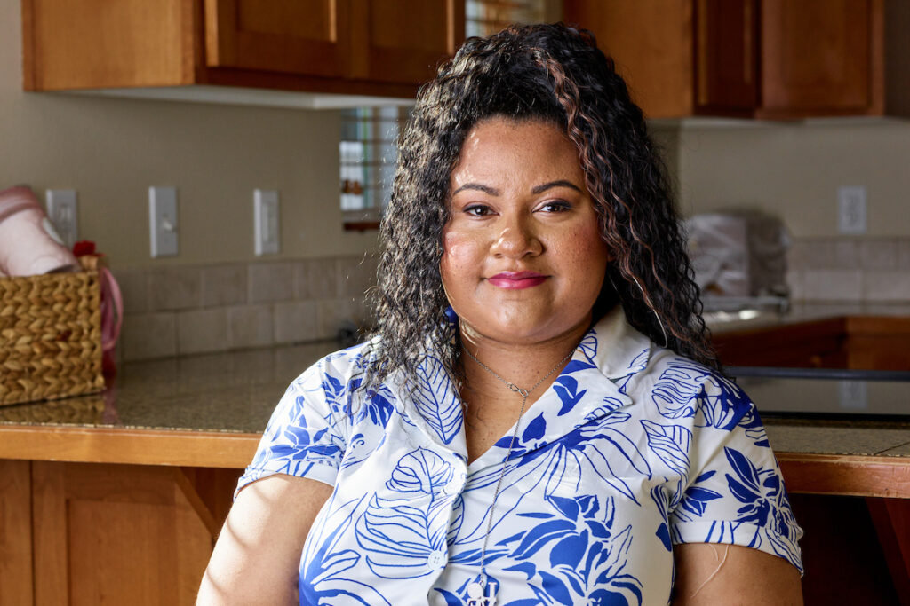 Woman in blue and white patterned dress, sitting in a kitchen