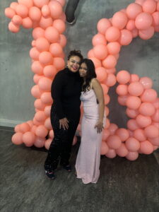 Photo of two women standing in front of pink balloons